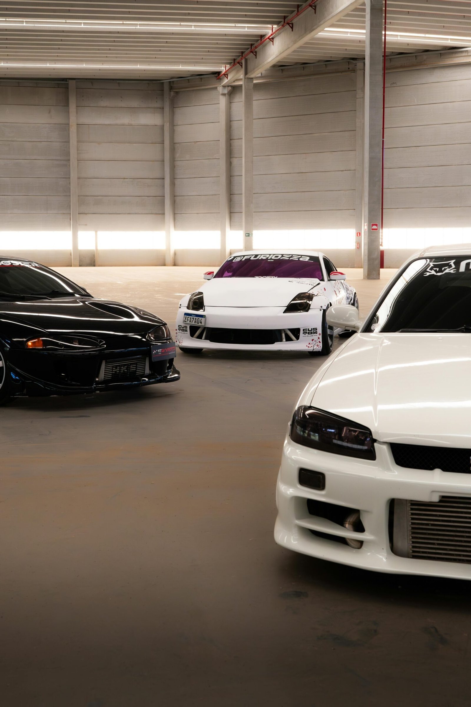 Services Three high-performance sports cars showcased in a modern indoor garage setup.