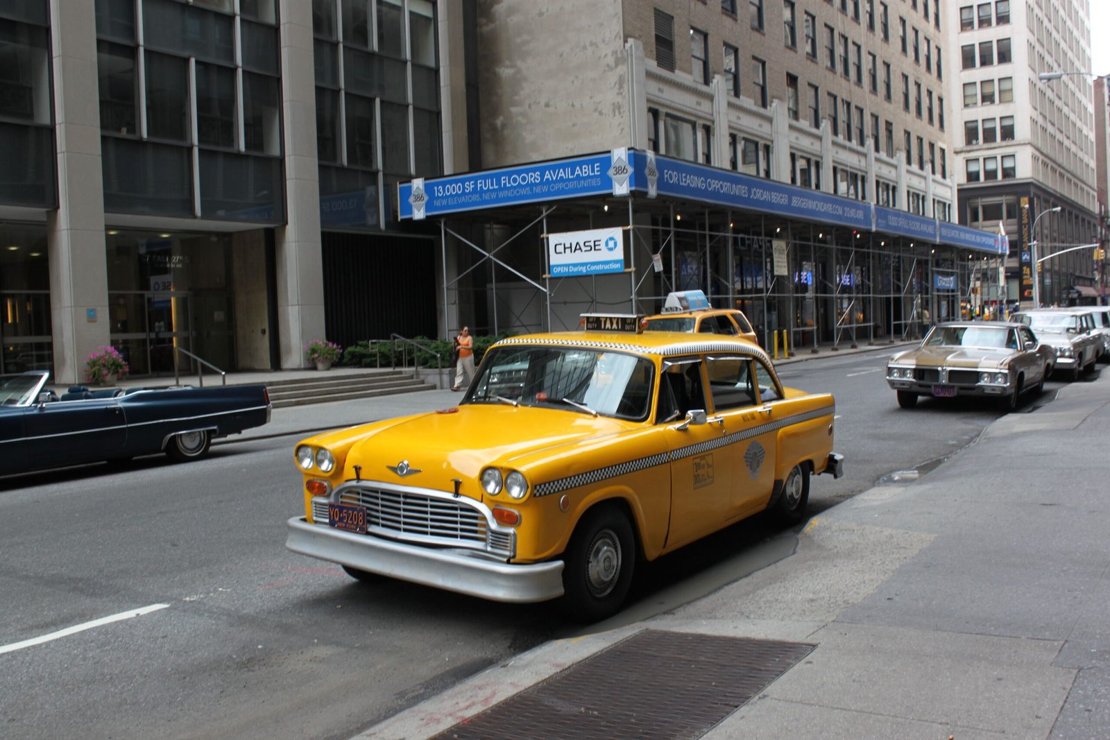 Vintage yellow taxi cab parked on a bustling New York City street.